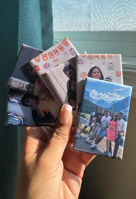 Hand holding a fan of glossy 2×3 photo magnets to show size and thickness